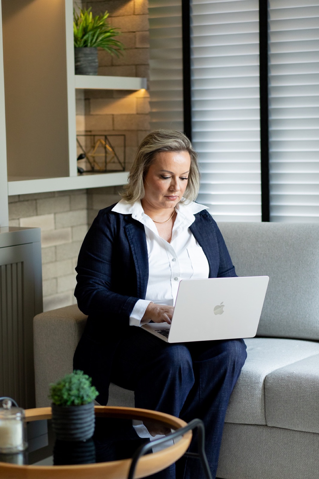 Fabiana Carvalho, fundadora da Valense, sentada no sofá com o laptop, preparando um treinamento de equipe